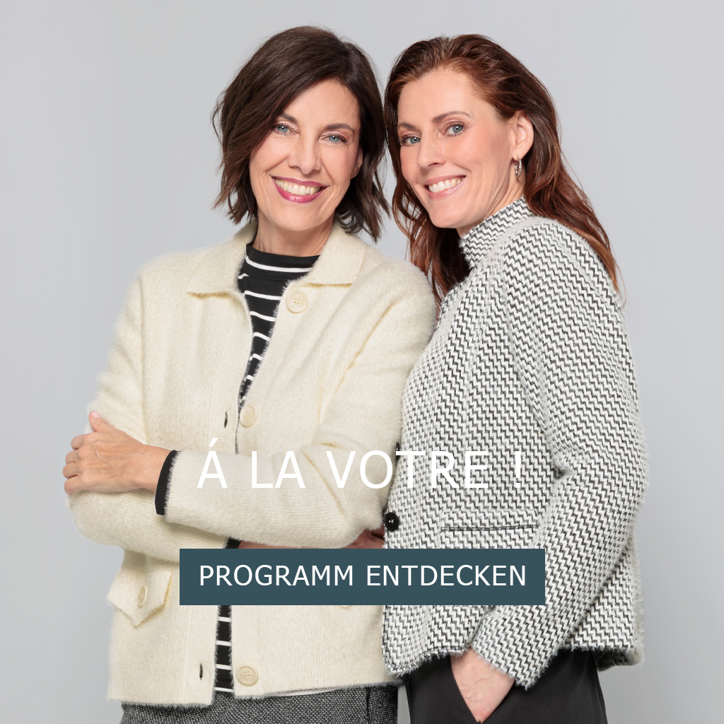Zwei Frauen in schicken Jacken stehen dicht beieinander und lächeln in die Kamera vor einem schlichten grauen Hintergrund. Der Text überlagert das Bild und lautet À LA VOTRE und PROGRAMM ENTDECKEN.