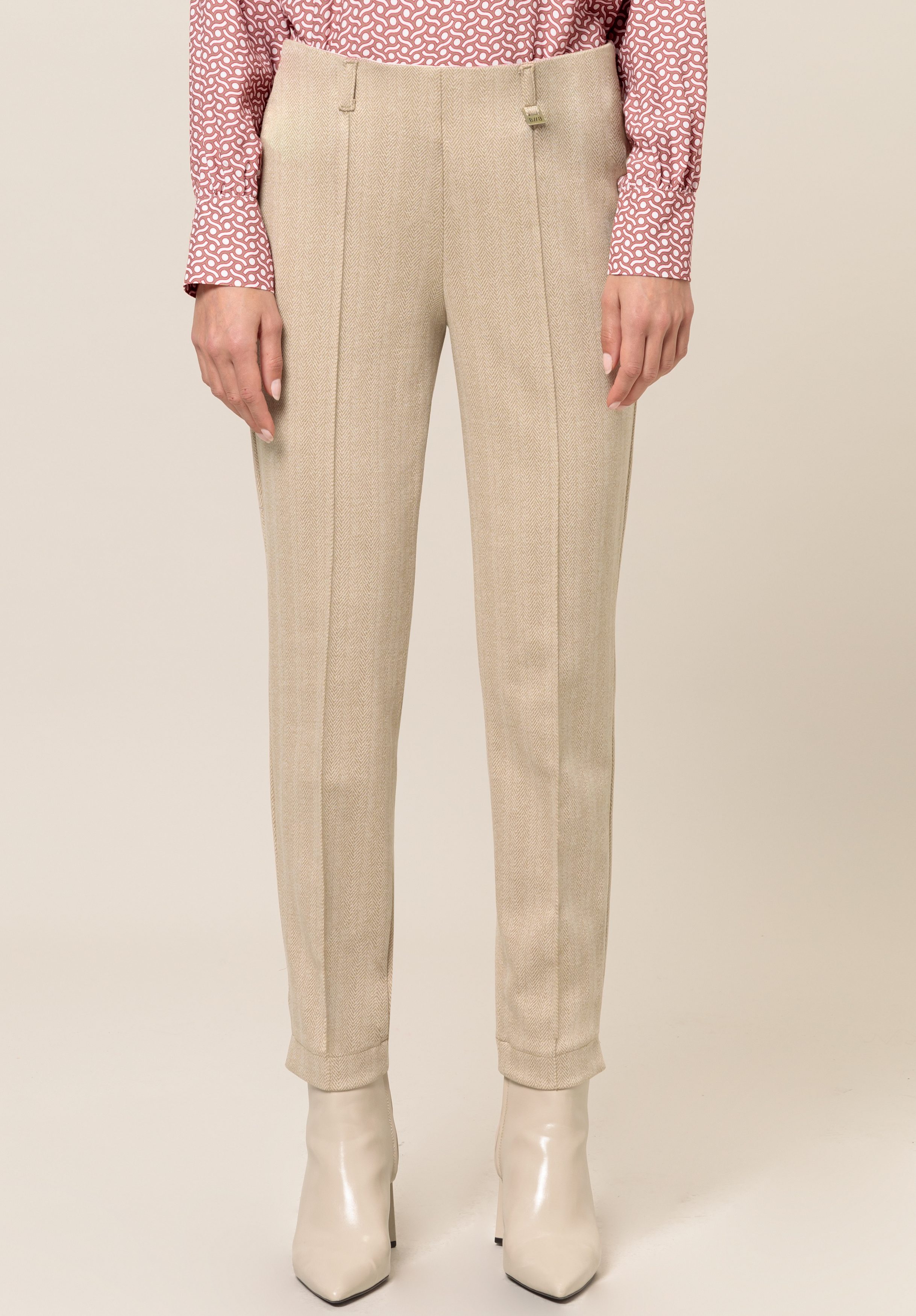 Jeggings DENVER Eine Person trägt beigefarbene Hosen, ein rosa gemustertes Langarmhemd und cremefarbene Stiefeletten vor einem schlichten hellen Hintergrund. Das Bild ist an den Schultern abgeschnitten, um das Outfit hervorzuheben.