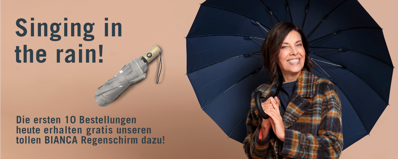 Eine lächelnde Frau in einem karierten Mantel hält einen aufgespannten marineblauen Regenschirm. Text: Singing in the rain! Die ersten 10 Bestellungen heute erhalten gratis unseren tollen BIANCA Regenschirm dazu!