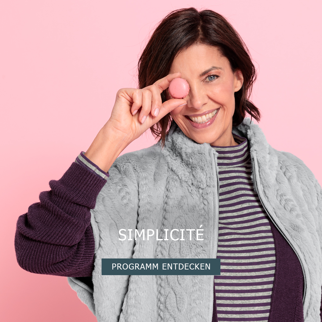 Eine lächelnde Frau in einer grauen Kunstpelzweste und einem gestreiften Pullover hält ein rosa Macaron über ein Auge vor einem rosa Hintergrund. Der Text lautet Simplicité Programm entdecken.