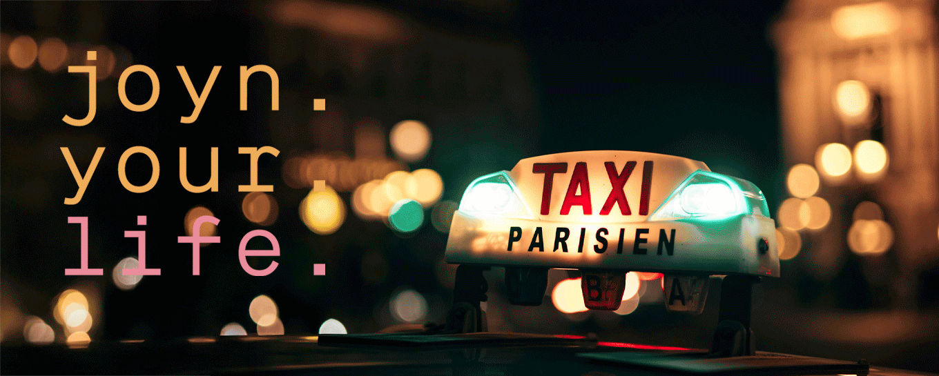 Ein leuchtendes Pariser Taxischild ist bei Nacht mit verschwommenen Lichtern im Hintergrund zu sehen. Der überlagerte Text lautet: joyn. your. life. in fetten, bunten Buchstaben.