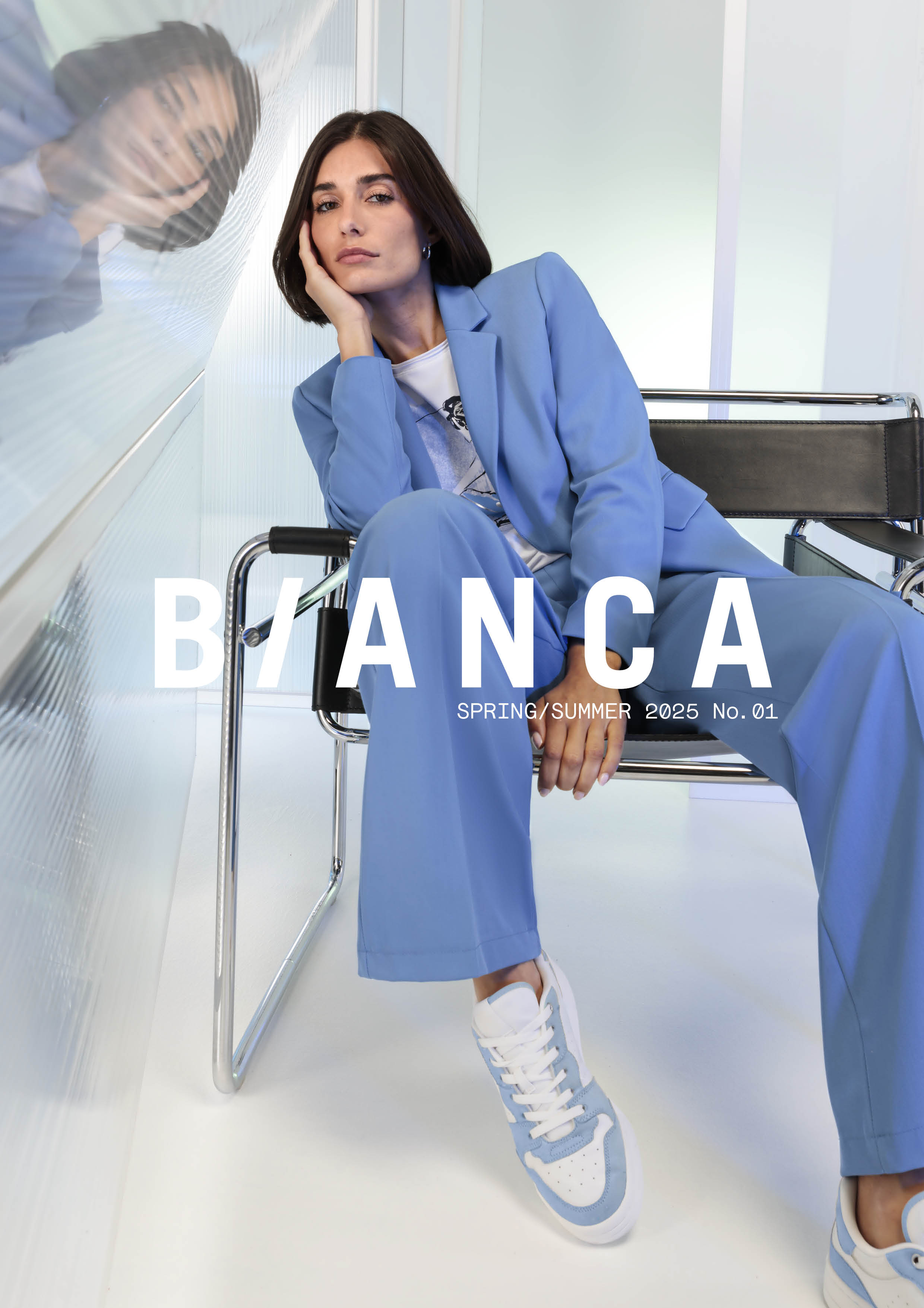 Eine Frau in hellblauem Anzug und Turnschuhen sitzt auf einem schwarzen Stuhl und stützt ihren Kopf auf ihre Hand. Ihr Spiegelbild erscheint in einer Glaswand neben ihr. Text: BIANCA FRÜHJAHR/SOMMER 2025 Nr. 01.