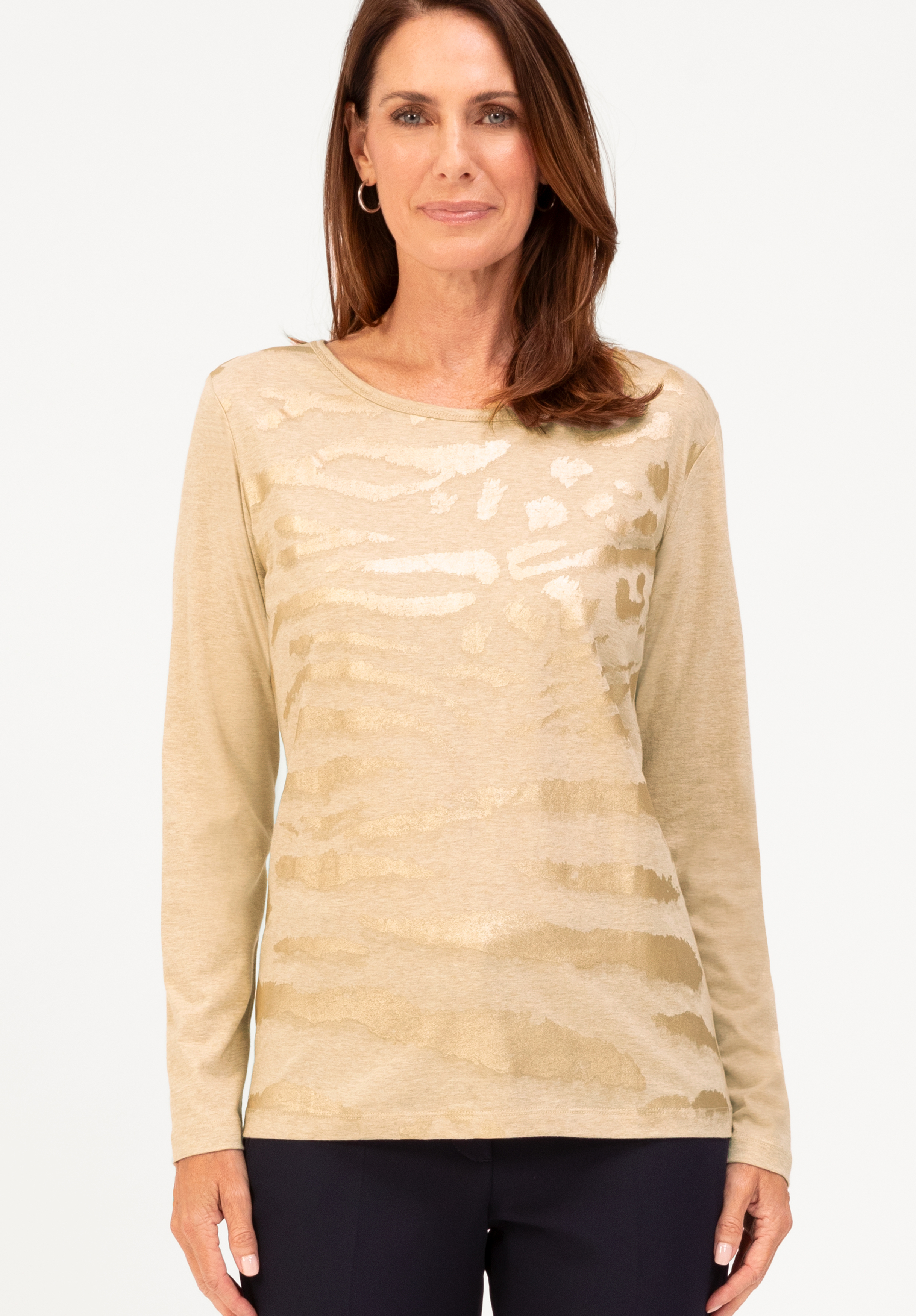 Langarmshirt DAMI Eine Frau mit mittellangen braunen Haaren trägt ein beigefarbenes, langärmeliges Oberteil mit dezentem Tiermuster und eine dunkle Hose, die vor einem schlichten weißen Hintergrund steht. Sie lächelt sanft und blickt nach vorne.